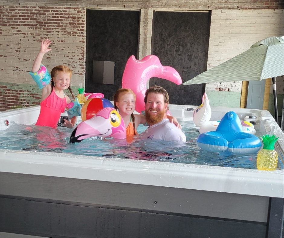 dad and children playing in Splash series ondisplay in pdc spas showroom