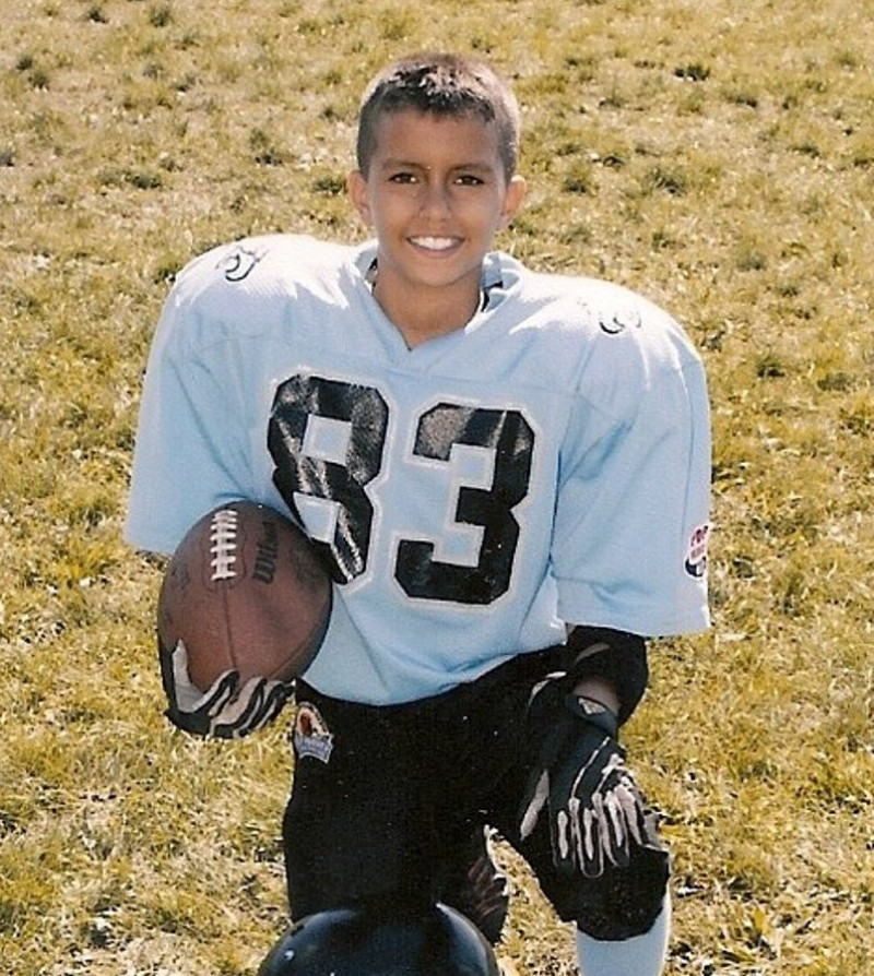 Josh Rojas smiling and posing in a team football uniform holding a football in his right hand