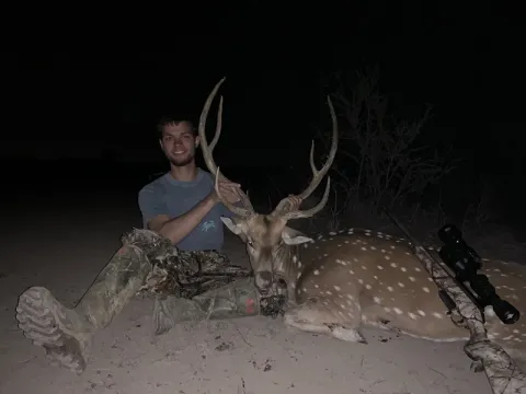 hunter with axis buck at night