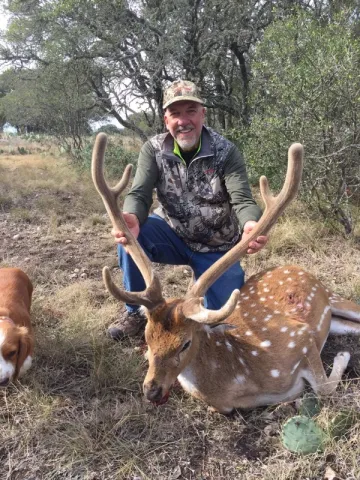 single hunter posing with axis buck trophy