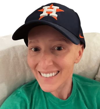 woman smiling wearing a navy blue cap with an orange star and h logo and a green shirt