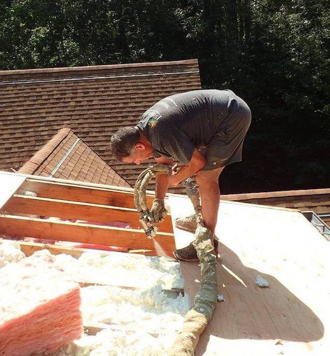 Man spraying foam insulation on a residential roof