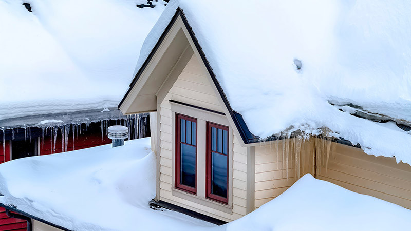 snow and icicles on the roof of a house