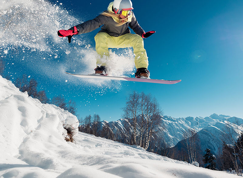 woman snowboarding in the air with snow powder