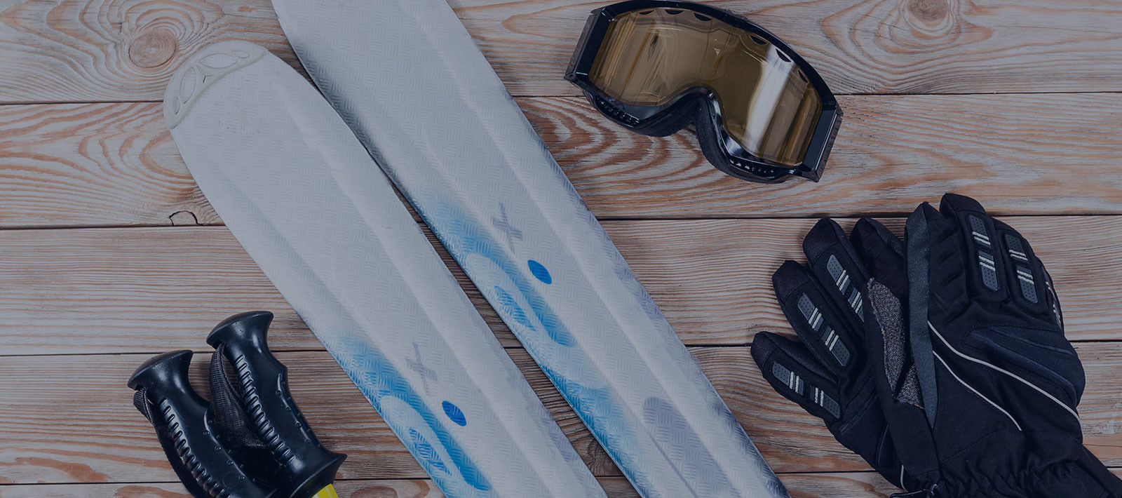 skis, goggles, poles and gloves on wood background