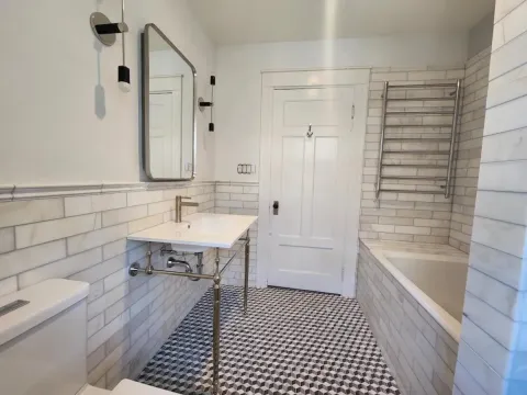 a bathroom with black and white tiled floors and beige shower tiles
