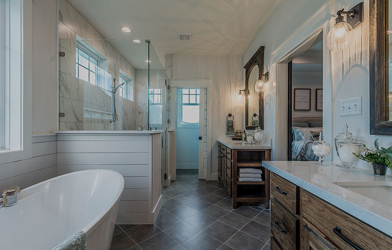 Modern bathroom with a freestanding tub, glass shower, and wooden vanities with mirrors.
