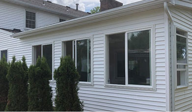 new sunroom addition with white siding by class a construction