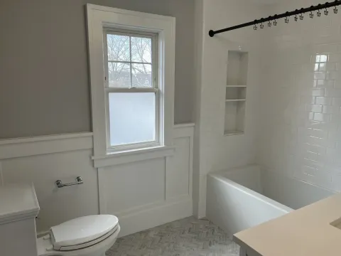a clean bathroom with white features and grey walls