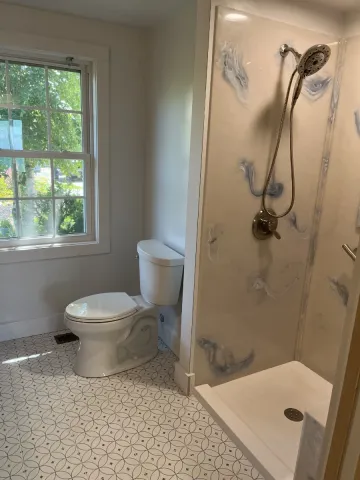 A new white and blue patterned shower and white toilet