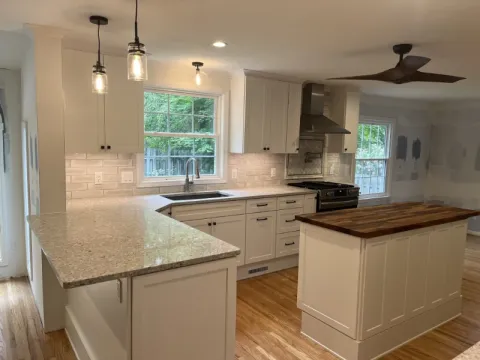 Modern kitchen with white cabinets, pendant lights, center island, and large window over sink.