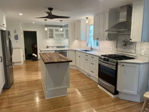 Modern kitchen with white cabinets, wood island, stainless appliances, and hardwood floors.