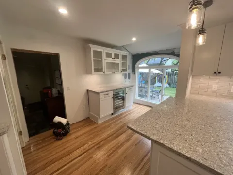 Bright kitchen with wood floors, granite counters, and large glass doors opening to backyard.