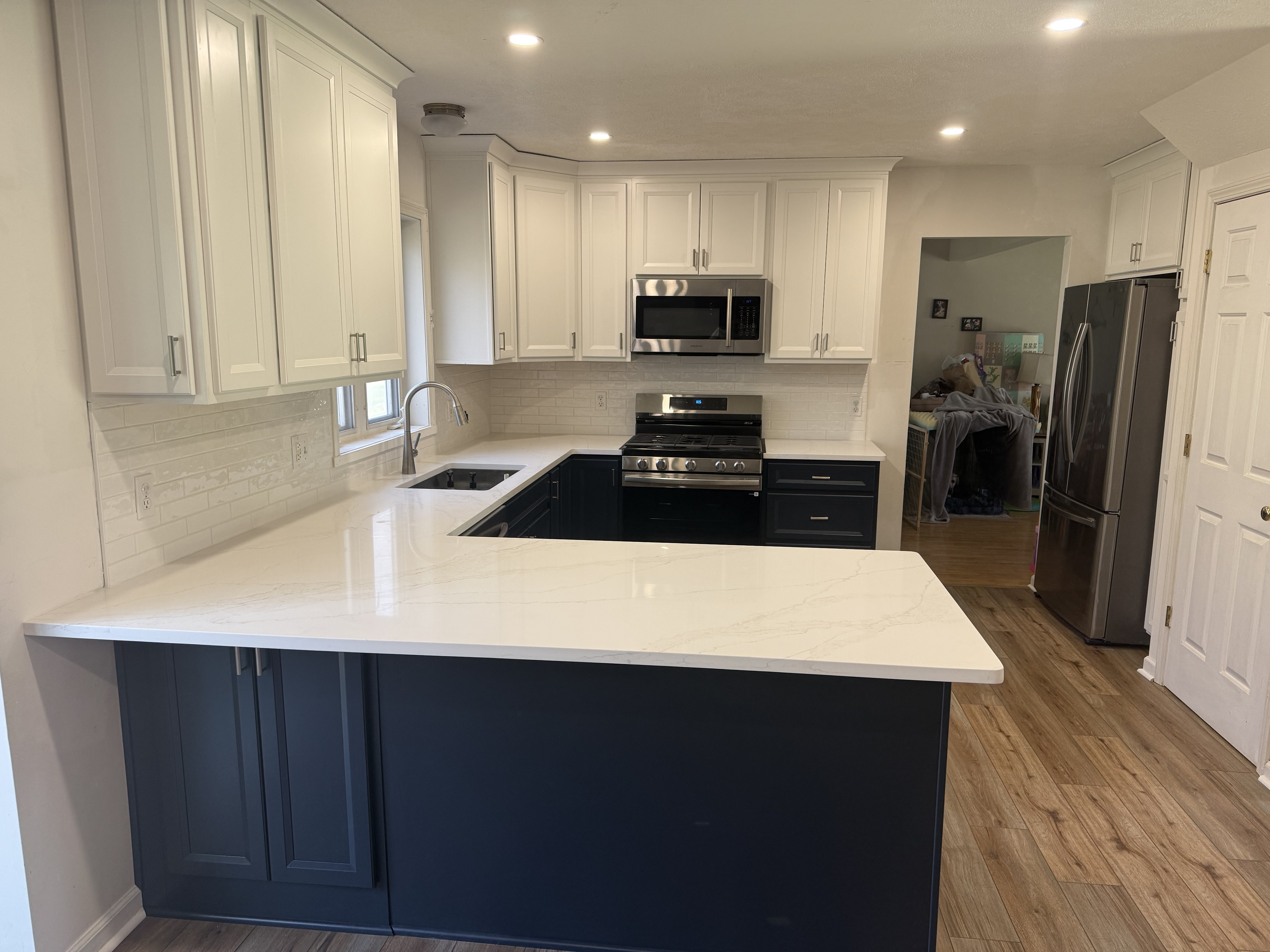 Modern kitchen with white cabinets, dark lower cabinets, and white marble countertops.