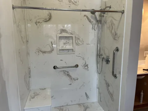 A new shower and tub with gray swirling patterns on the walls.