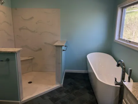 A white bathtub next to a shower stall in a bathroom with blue walls.