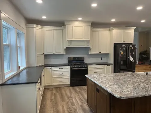 Modern kitchen with white cabinets, black appliances, and a marble island countertop.