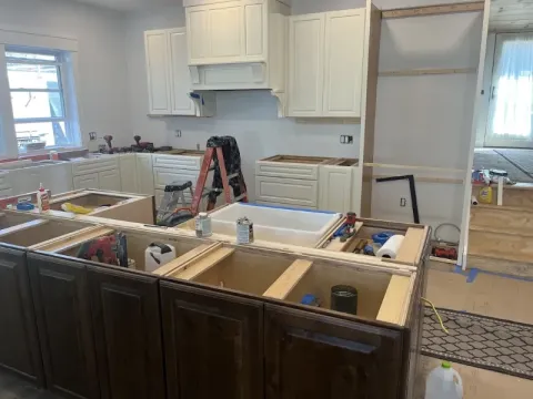 Kitchen under renovation with cabinets being installed, tools and supplies scattered around.