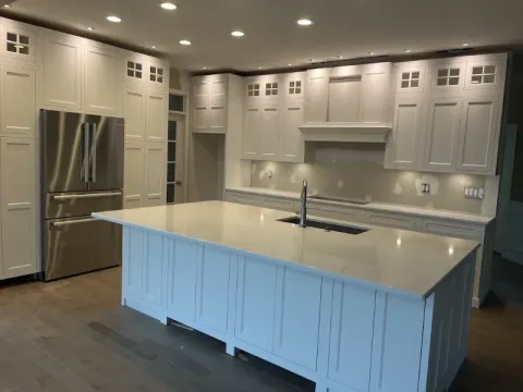 Modern kitchen with white cabinets, stainless steel fridge, and large island with sink.