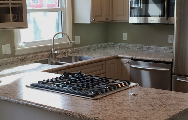 Modern kitchen with marble countertops, gas stove, stainless steel appliances, and a sink.