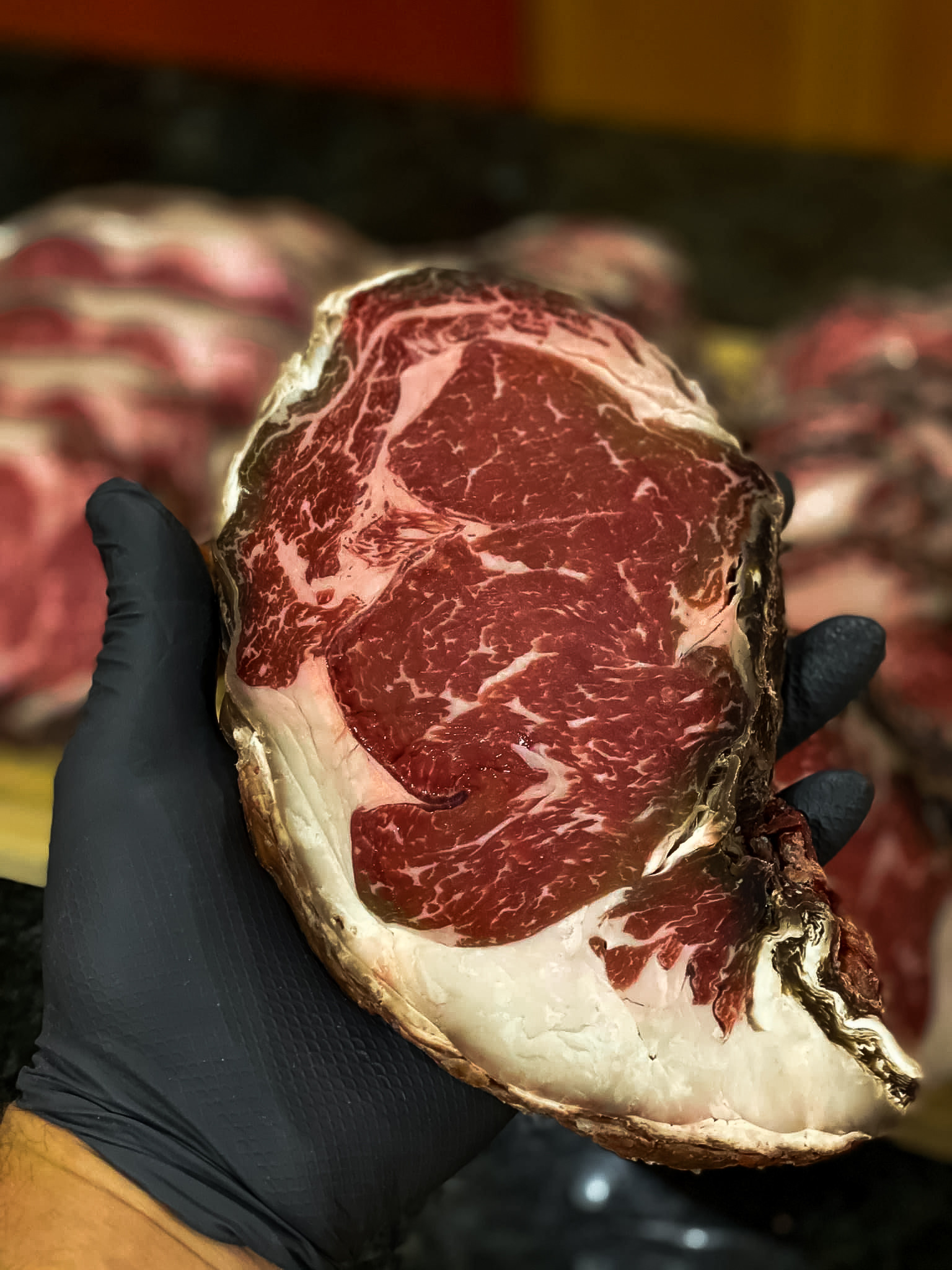 gloved hand holding slice of dry aged beef