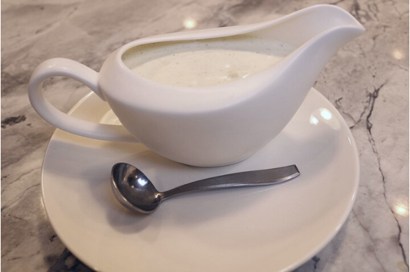 roquefort dressing in white porcelain gravy boat with small ladel
