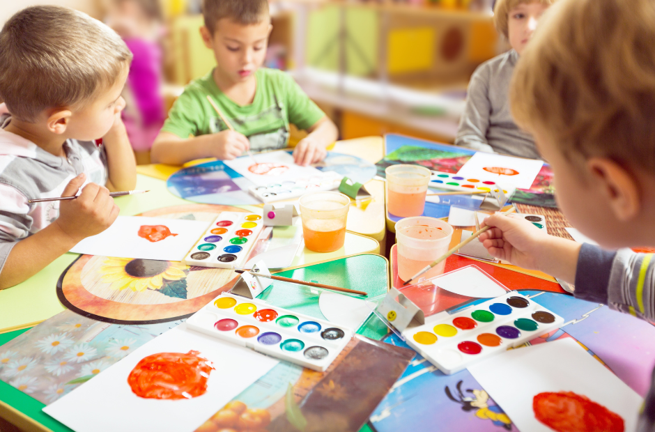 Children sitting on the floor in a circle coloring with colored pencils.