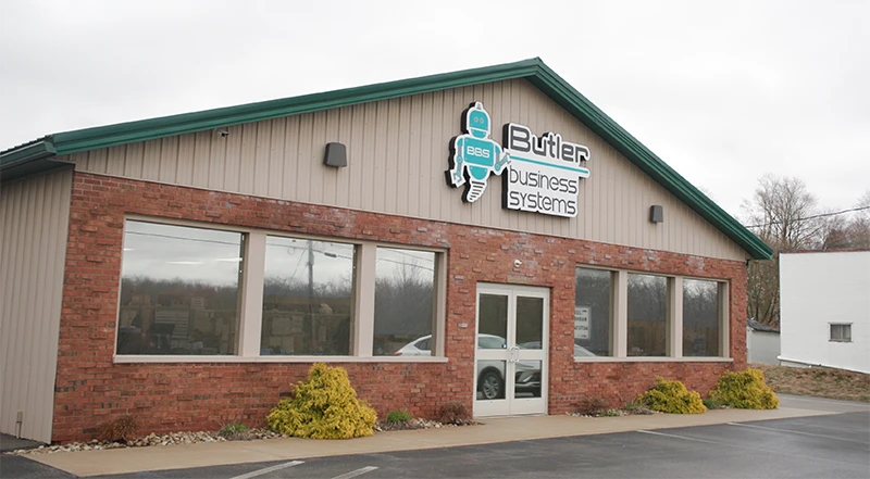 A brick building with a Butler Business Systems sign and large front windows.