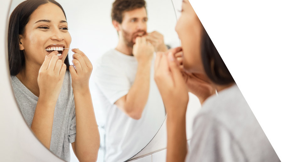 couple flossing teeth in mirror