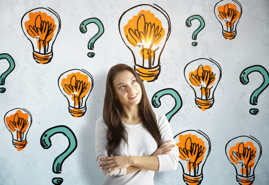girl standing in front of a wall with question marks and light bulbs painted on it