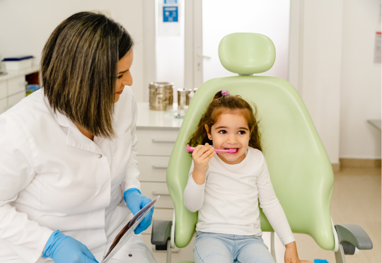 small child brushing her teeth at the dentist