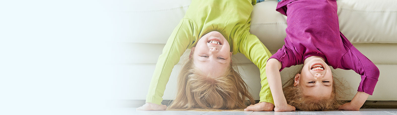 Two children holding themselves upside down and smiling.