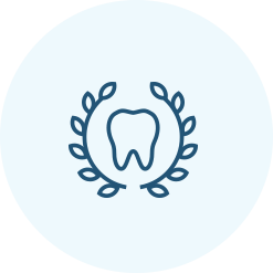 Outline of a tooth surrounded by a laurel wreath on a light blue circular background.